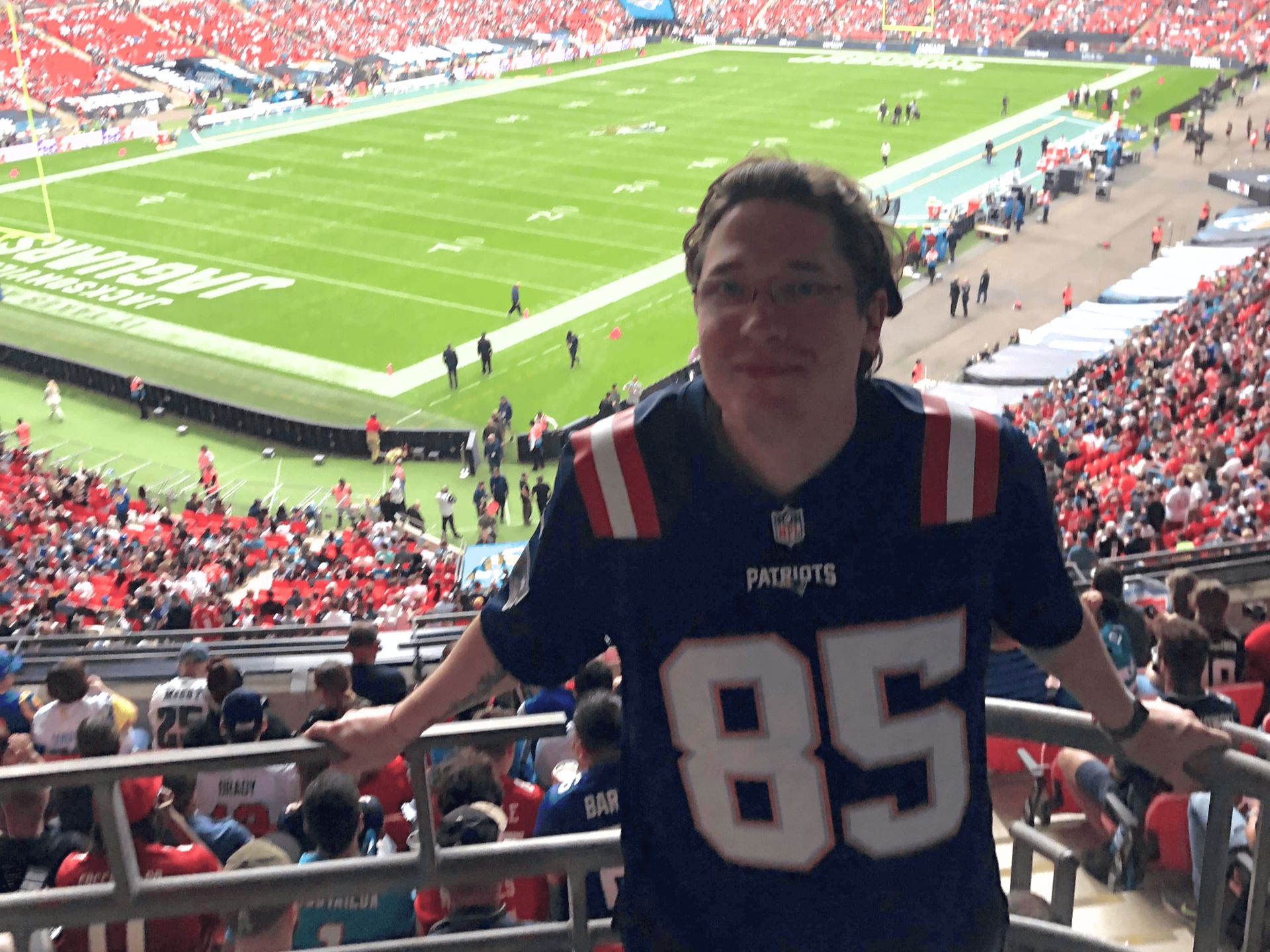 Fanclub-Mitglied im Patriots-Jersey im Stadion, im Hintergrund das Spielfeld