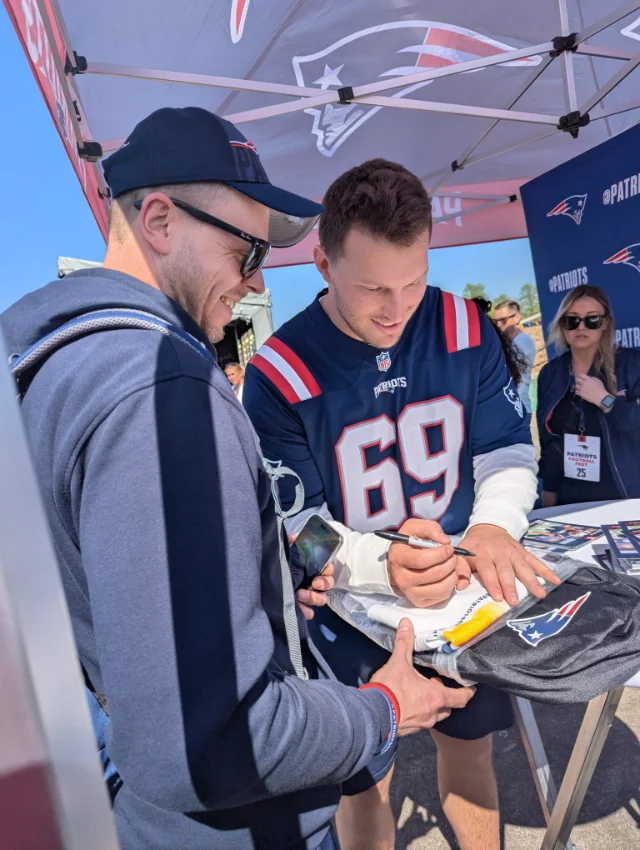 Ein Patriots-Pavillon, in dem ein Mitglied und der ehemalige Spieler Cole Strange steht.
