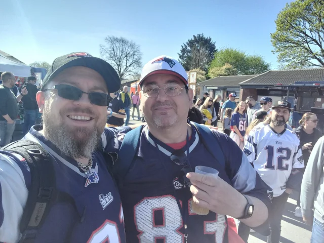 Ein Selfie von zwei Mitgliedern, im Hintergrund sind andere Patriots-Fans zu sehen.