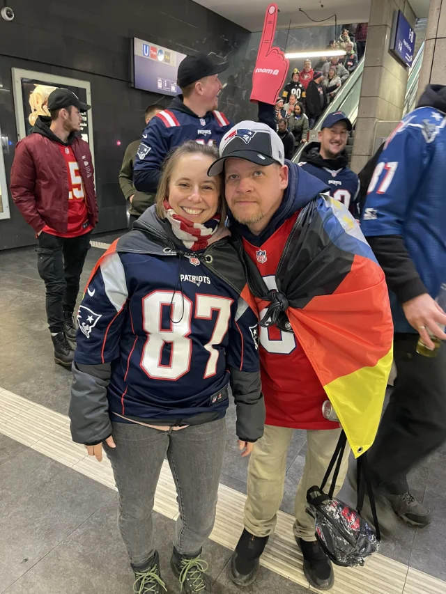 Zwei Mitglieder im Patriots-Gear posieren für die Kamera.