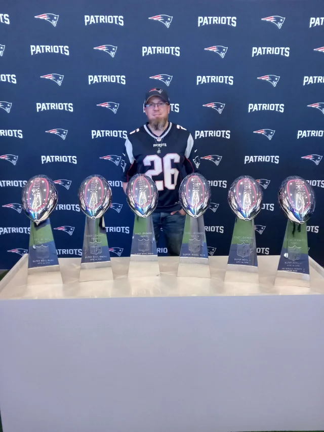 Ein Mitglied steht hinter den Lombardy-Trophys.
