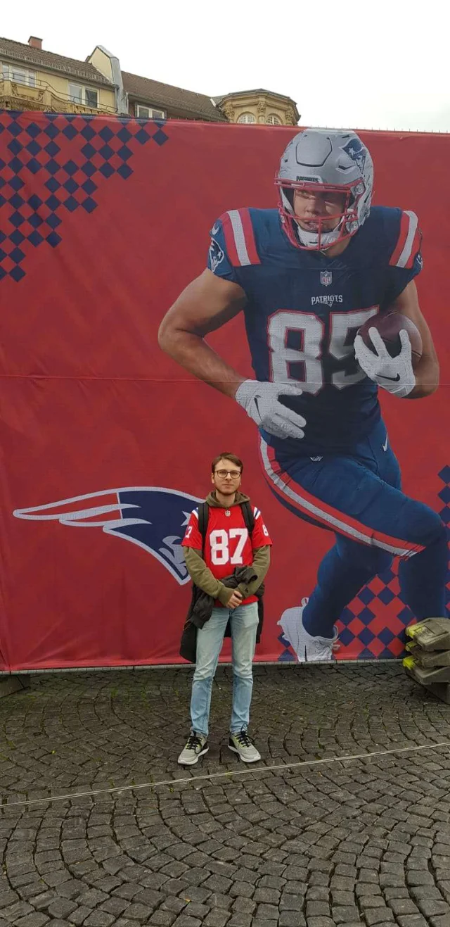 Ein Mitglied steht vor einem großen Hunter Henry Wandbild.