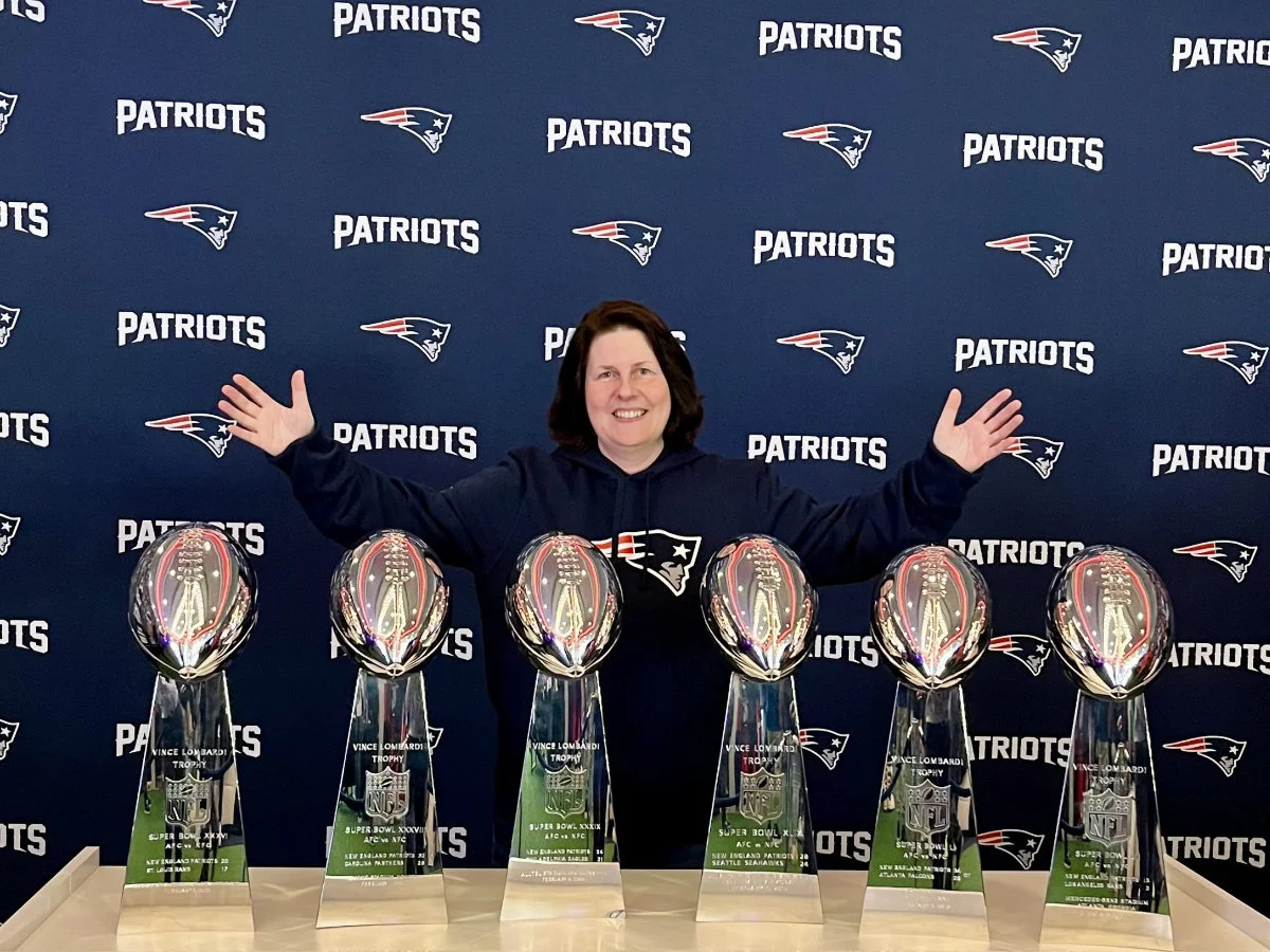 Ein Mitglied steht hinter den sechs Lombardi-Trophys der Patriots.