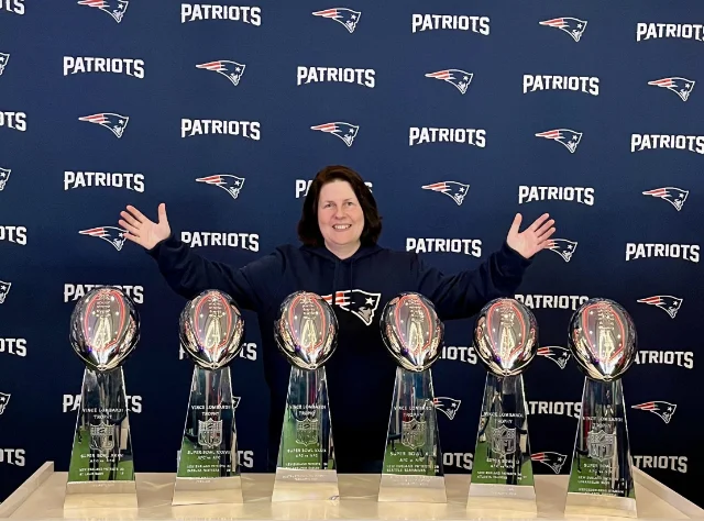 Ein Mitglied steht hinter den sechs Lombardi-Trophys der Patriots.