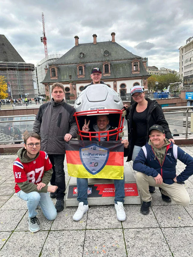Fünf Mitglieder stehen um einen überdimensionalen NFL-Helm, einer hockt darunter und hält eine Fanclub-Fahne.