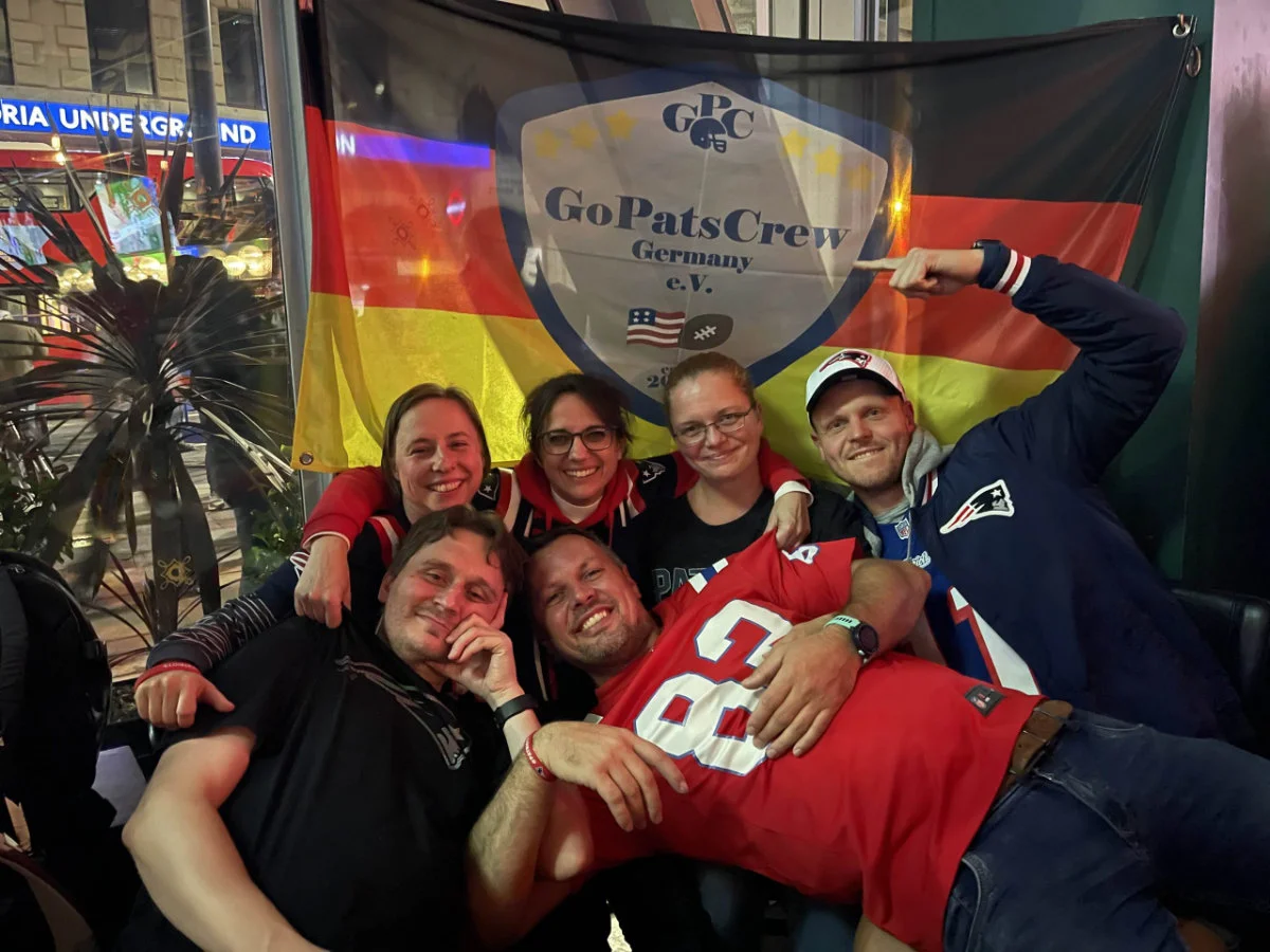 Sechs Mitglieder der GoPatsCrew vor der Fanclub-Fahne in einem Pub in London.