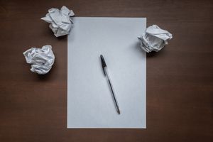 Crumpled paper and pen on desk, symbolizing writer's block or creativity struggles.